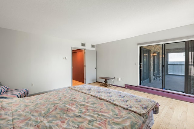 bedroom with access to exterior and light hardwood / wood-style flooring