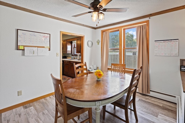 dining room featuring ceiling fan, sink, crown molding, light hardwood / wood-style floors, and a textured ceiling