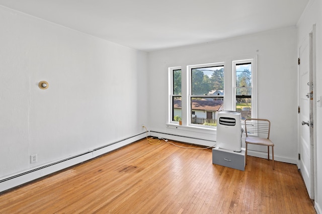 spare room featuring wood-type flooring and a baseboard heating unit