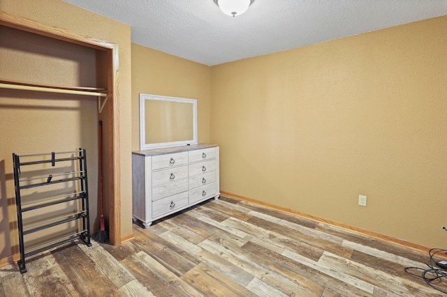 unfurnished bedroom featuring a textured ceiling, light hardwood / wood-style floors, and a closet