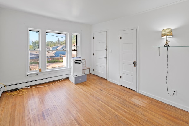 unfurnished bedroom with light wood-type flooring and a baseboard heating unit