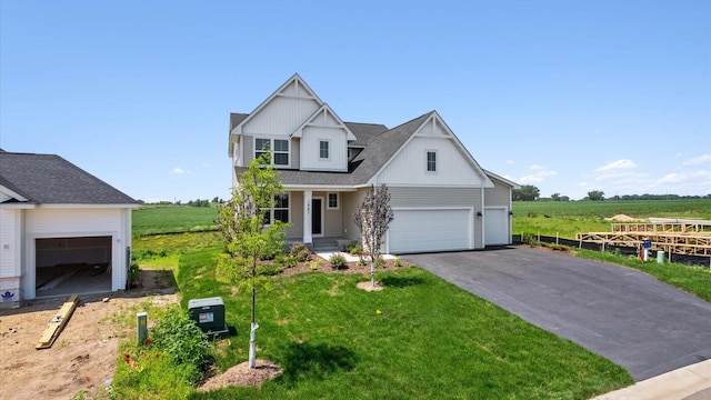 view of front of home featuring a garage, a front lawn, and a rural view