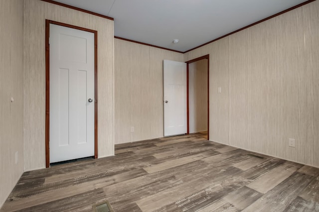 unfurnished bedroom with hardwood / wood-style floors, a closet, and ornamental molding