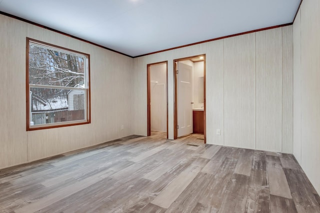 unfurnished bedroom featuring light hardwood / wood-style floors, ensuite bath, a closet, and crown molding