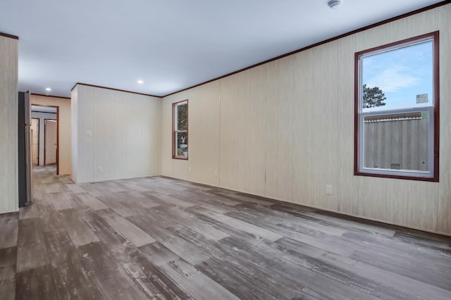 empty room featuring wood-type flooring and ornamental molding