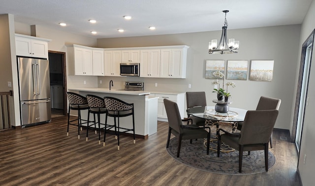 dining room featuring sink, dark wood-type flooring, and a chandelier