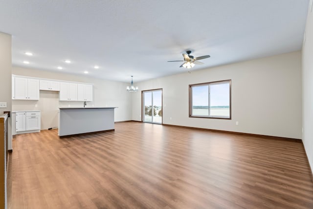 unfurnished living room featuring ceiling fan with notable chandelier and light hardwood / wood-style floors