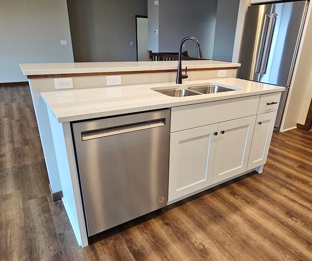 kitchen with sink, white cabinetry, stainless steel appliances, dark wood-type flooring, and a kitchen island with sink