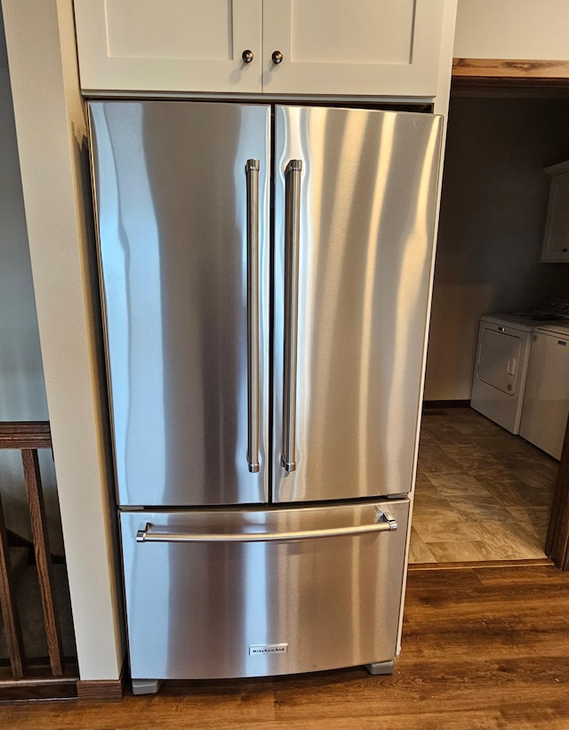 details with white cabinetry, high end fridge, dark wood-type flooring, and washing machine and clothes dryer