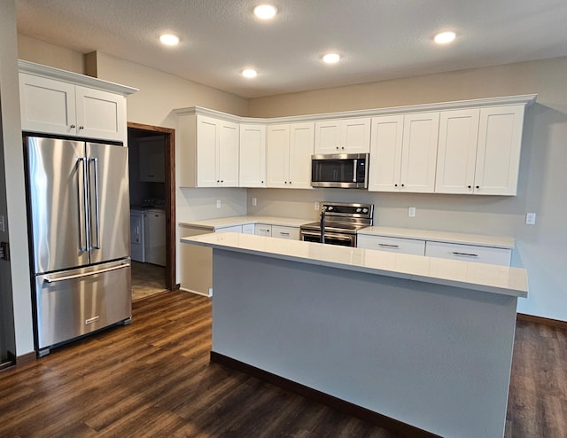 kitchen with washing machine and dryer, stainless steel appliances, a center island, dark wood-type flooring, and white cabinets