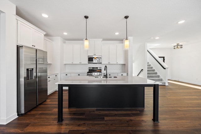 kitchen featuring dark hardwood / wood-style flooring, appliances with stainless steel finishes, pendant lighting, and white cabinetry