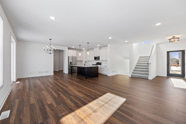 unfurnished living room with a notable chandelier, a healthy amount of sunlight, dark hardwood / wood-style floors, and sink