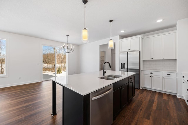 kitchen with pendant lighting, an island with sink, decorative backsplash, appliances with stainless steel finishes, and sink