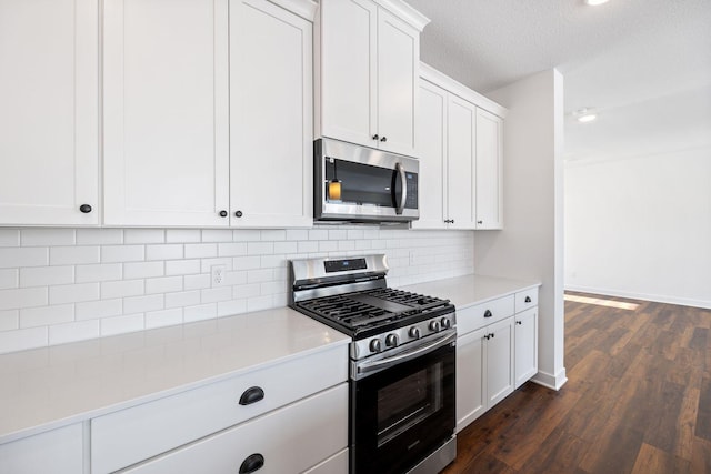 kitchen with a textured ceiling, stainless steel appliances, tasteful backsplash, dark hardwood / wood-style flooring, and white cabinets