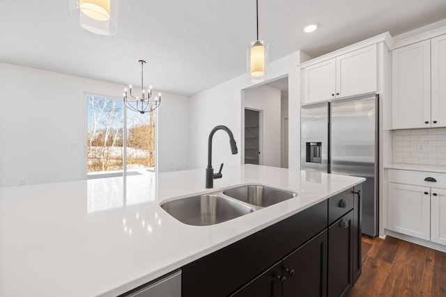 kitchen with stainless steel refrigerator with ice dispenser, sink, tasteful backsplash, and hanging light fixtures