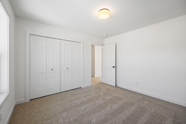 unfurnished bedroom with a closet and light carpet