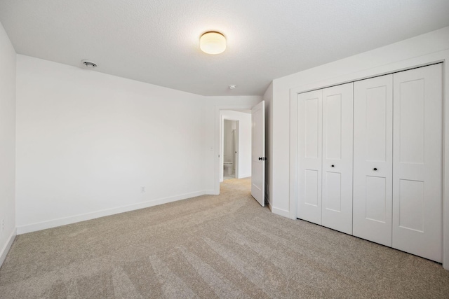 unfurnished bedroom with a textured ceiling, a closet, and light carpet