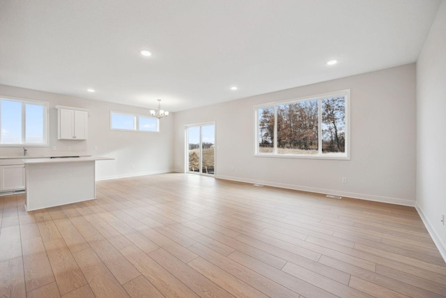 unfurnished living room with a notable chandelier, light hardwood / wood-style floors, and sink