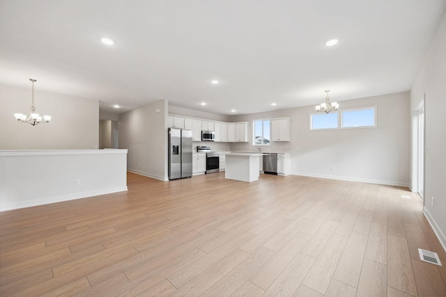 unfurnished living room with light hardwood / wood-style floors and an inviting chandelier