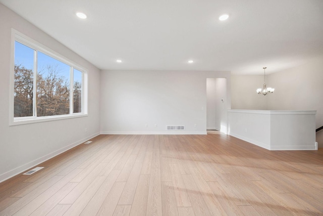 spare room featuring a notable chandelier and light hardwood / wood-style floors