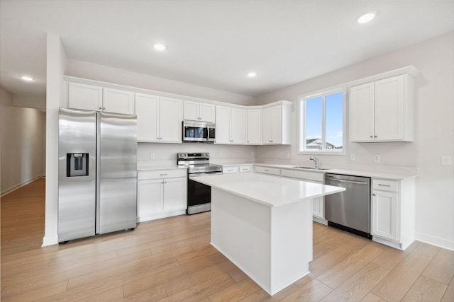 kitchen featuring a center island, sink, light hardwood / wood-style flooring, white cabinets, and appliances with stainless steel finishes