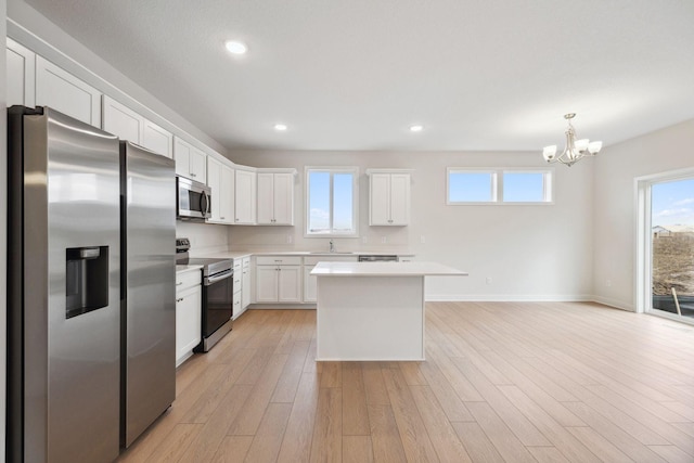 kitchen featuring light hardwood / wood-style floors, white cabinetry, stainless steel appliances, and a wealth of natural light