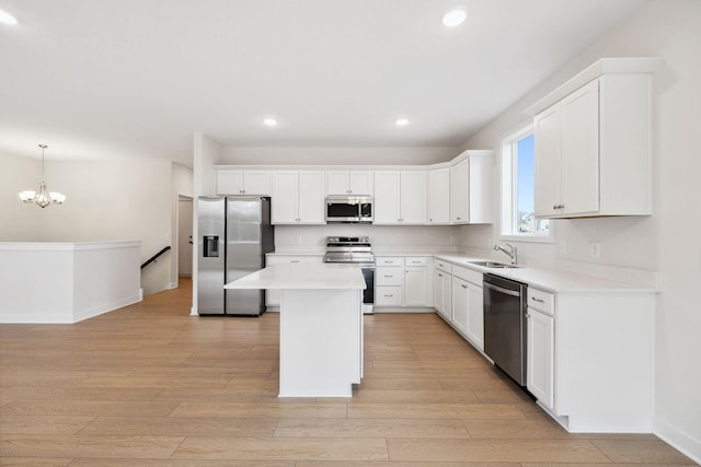 kitchen with sink, light hardwood / wood-style flooring, pendant lighting, a kitchen island, and appliances with stainless steel finishes