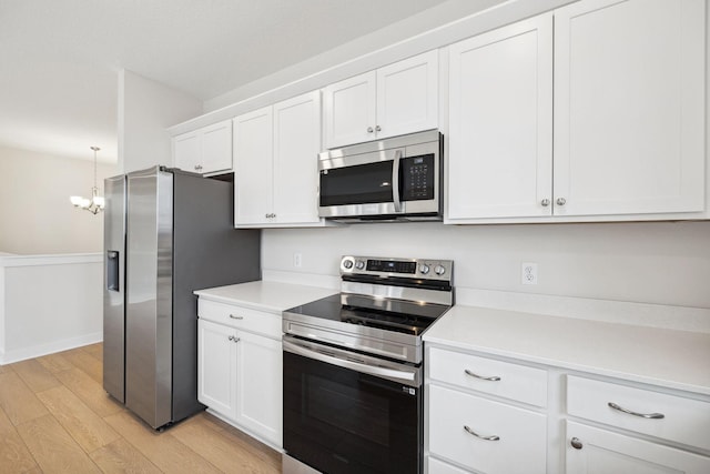 kitchen featuring pendant lighting, white cabinetry, appliances with stainless steel finishes, and light hardwood / wood-style flooring