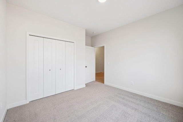 unfurnished bedroom with a closet and light colored carpet