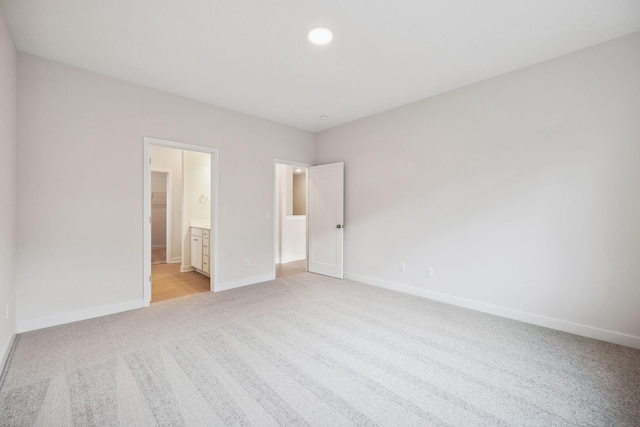 unfurnished bedroom with connected bathroom and light colored carpet