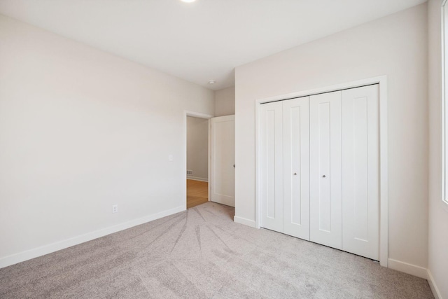 unfurnished bedroom with light colored carpet and a closet