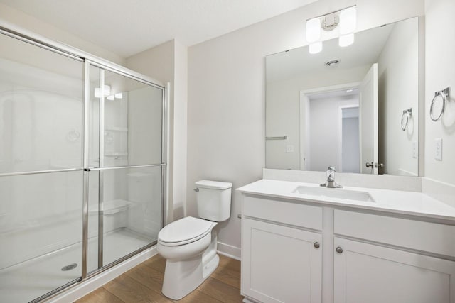 bathroom with wood-type flooring, vanity, toilet, and a shower with shower door