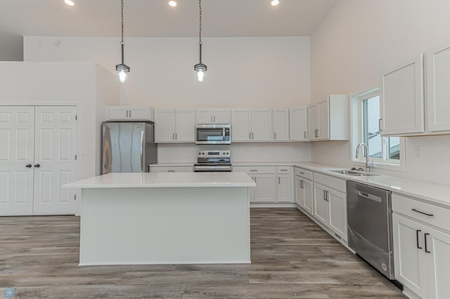 kitchen with hanging light fixtures, appliances with stainless steel finishes, sink, and a center island