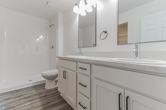 bathroom with a shower, hardwood / wood-style floors, toilet, and vanity