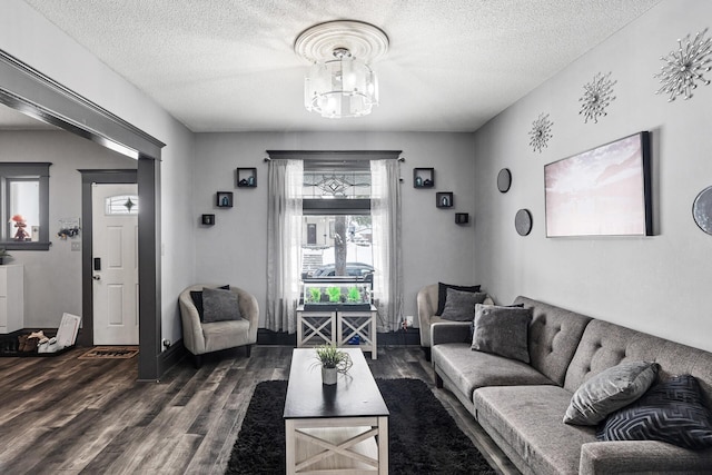 living room featuring dark hardwood / wood-style flooring, a textured ceiling, and an inviting chandelier