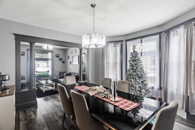 dining room featuring a chandelier, a textured ceiling, dark hardwood / wood-style flooring, and ornate columns