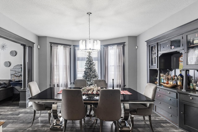 dining area featuring a textured ceiling, dark hardwood / wood-style floors, and an inviting chandelier