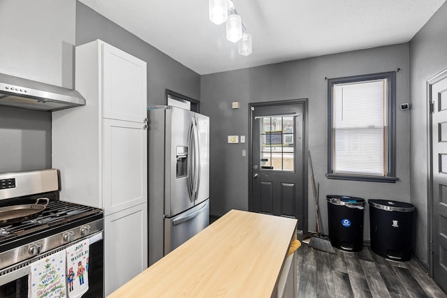 kitchen featuring wall chimney range hood, white cabinets, dark hardwood / wood-style floors, and appliances with stainless steel finishes