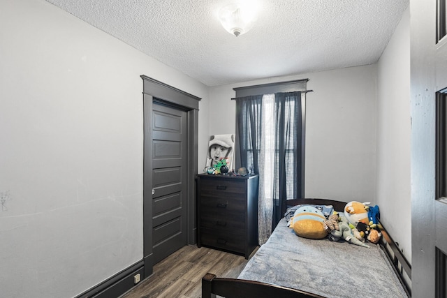 bedroom with a textured ceiling and dark hardwood / wood-style flooring