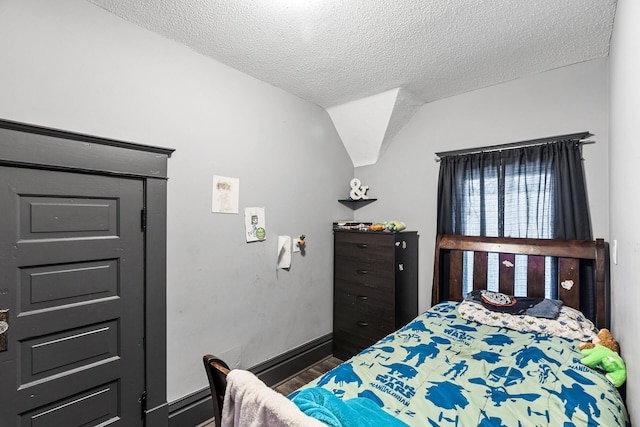 bedroom featuring lofted ceiling, a textured ceiling, and dark wood-type flooring