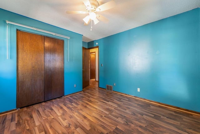 unfurnished bedroom with a textured ceiling, dark hardwood / wood-style flooring, a closet, and ceiling fan