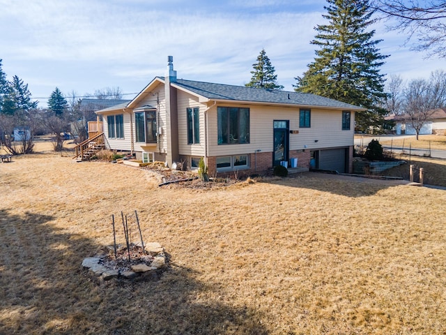 rear view of property featuring an attached garage, a yard, and fence