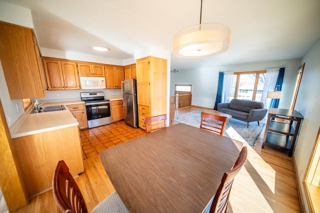 kitchen featuring light wood-style flooring, a sink, open floor plan, stainless steel appliances, and light countertops