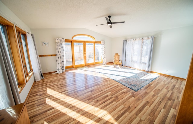 unfurnished room featuring wood finished floors, lofted ceiling, ceiling fan, french doors, and a textured ceiling