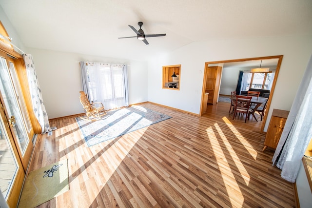 unfurnished living room featuring ceiling fan, baseboards, lofted ceiling, and wood finished floors