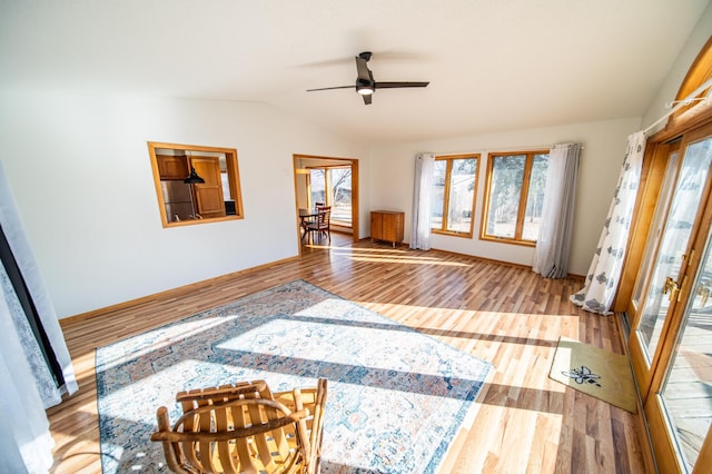 interior space featuring ceiling fan, baseboards, lofted ceiling, and wood finished floors