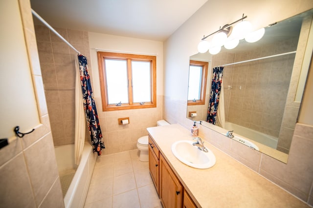 bathroom featuring tile patterned flooring, toilet, vanity, shower / bath combo, and tile walls