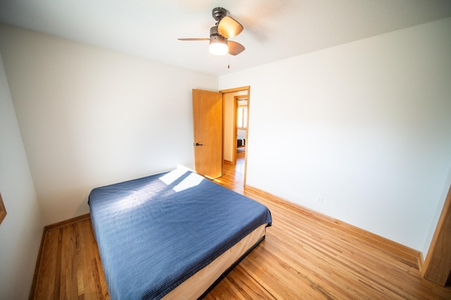 bedroom featuring baseboards, light wood-type flooring, and ceiling fan