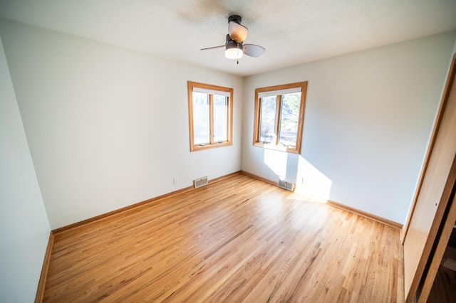 spare room featuring ceiling fan, a textured ceiling, visible vents, and light wood-type flooring