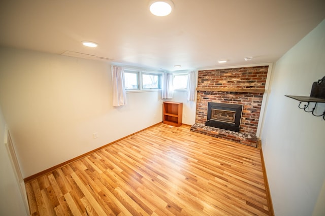 unfurnished living room featuring a fireplace, baseboards, and wood finished floors